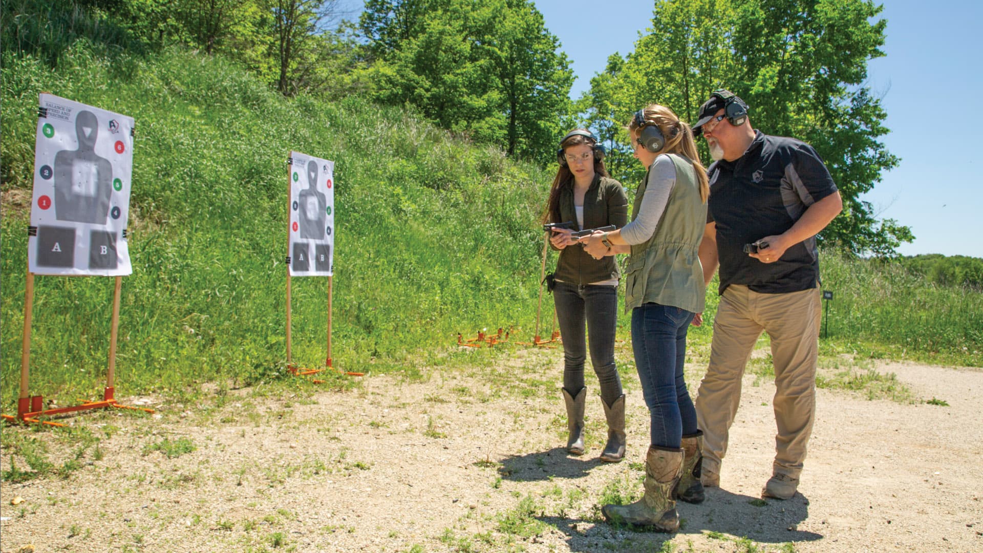 A certified instructor coaching a student at an outdoor range.